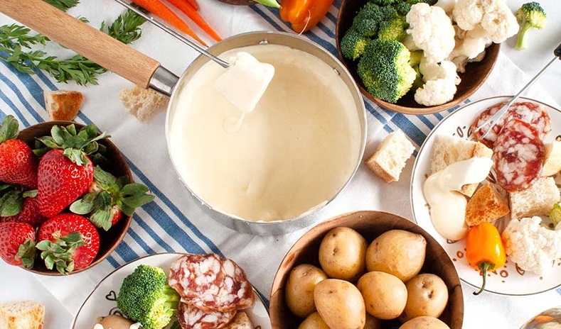 photo of a delicious fondue spread with melted cheese, bread and vegetables